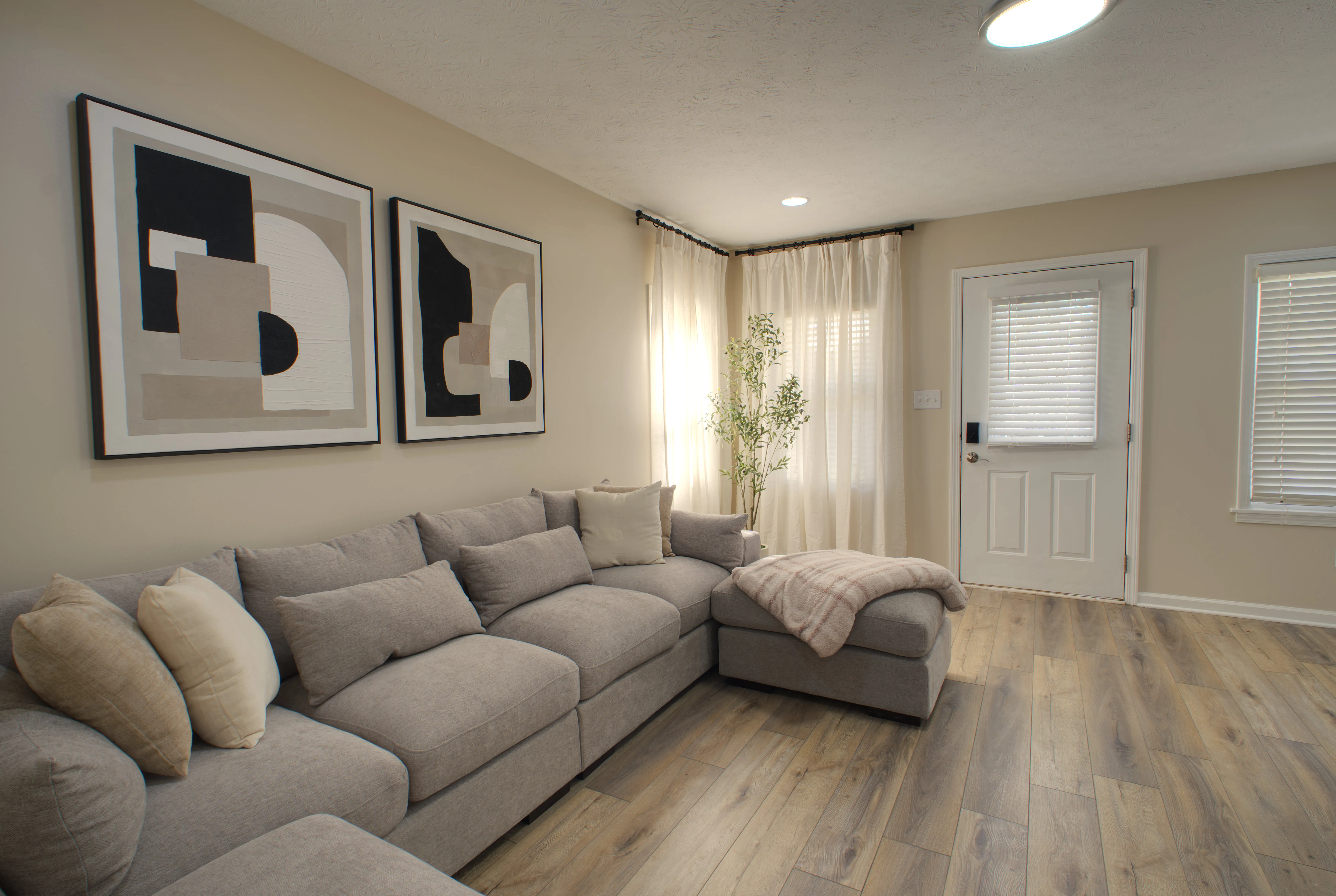 Living room with a large gray sectional and linen curtains